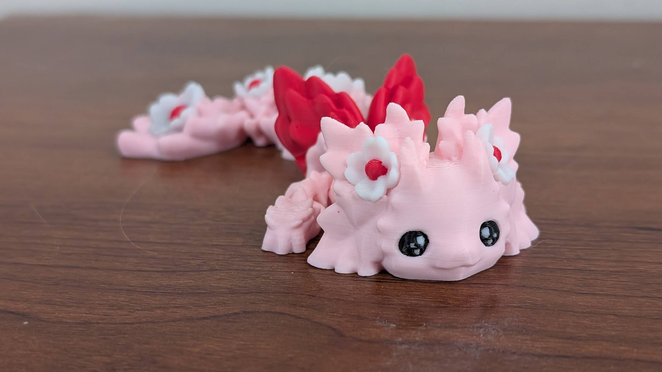 Pink articulated axolotl flower dragon with red and white flowers